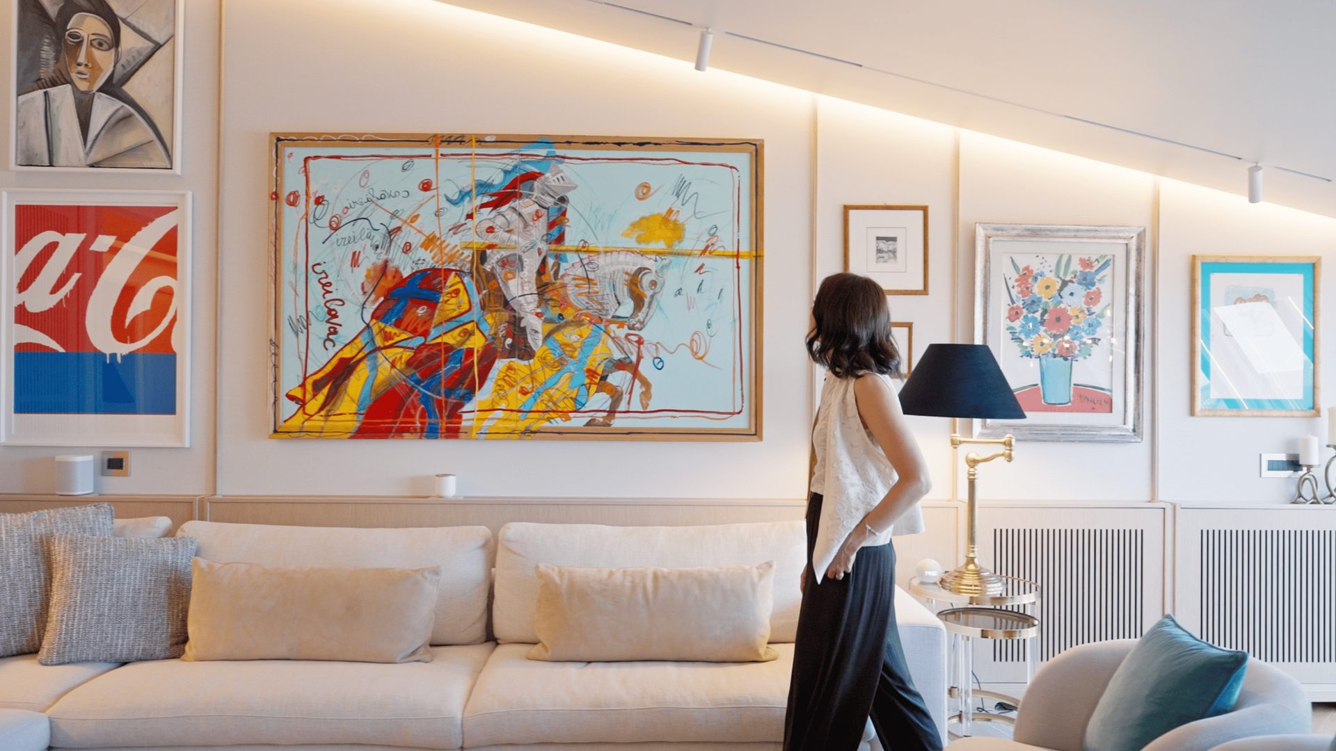 Soggiorno con divano chiaro, quadri colorati e dettagli di interior design